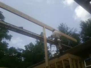Carpenter setting a ridge beam over a new addition frame — Ice Dam Removal by Roofing Brothers in Manitou Beach