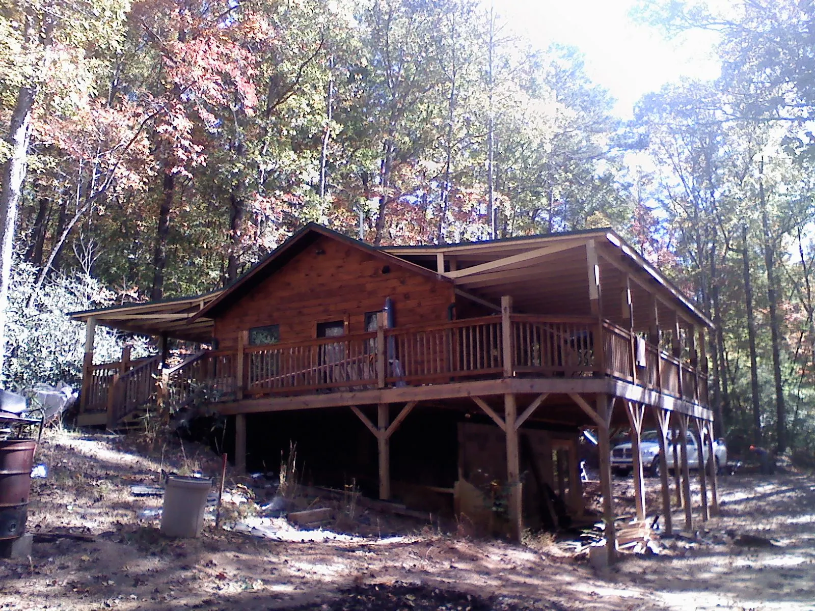 Log cabin with a wraparound porch and metal roof in the fall in Manitou Beach