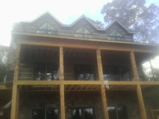 Dormers and porch framing on a large log home under construction — Roof Coating work by our crew in Manitou Beach