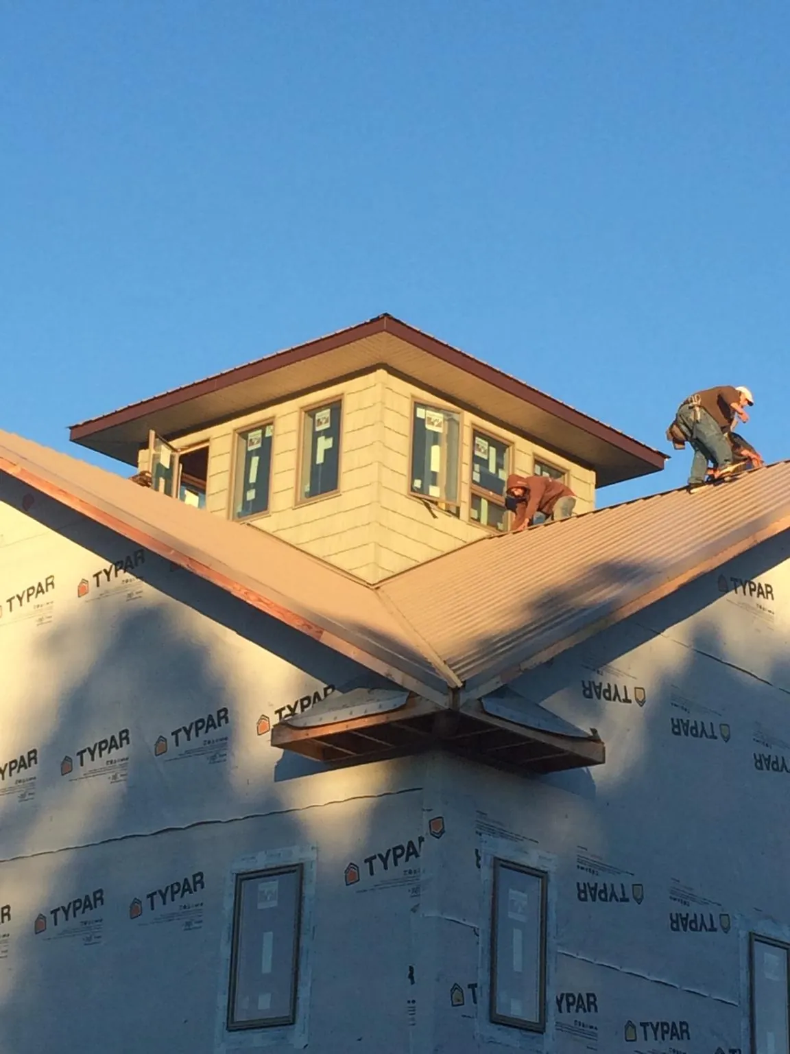 Roofers working around a rooftop cupola on a new metal roof at sunset — Roof Waterproofing in Manitou Beach by Roofing Brothers